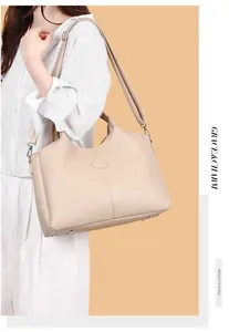Close-up detail of a large retro beige leather shoulder bag carried by a model