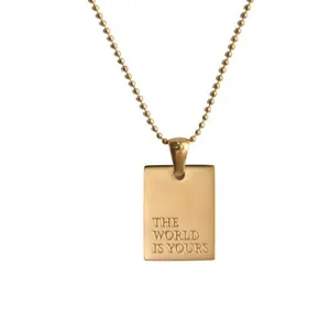 Gold stainless steel rectangular pendant necklace with "The World Is Yours" engraving.