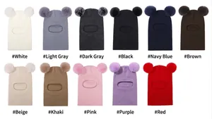 Detailed view of children's knitted balaclava hats in various solid colors with pom-poms
