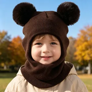Close-up detail of children's brown knitted balaclava with two large fur pom-poms for winter