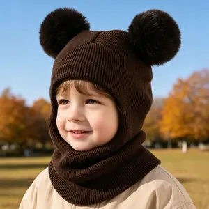 Detailed close-up of a cute brown knitted baby balaclava hat featuring double pom-poms