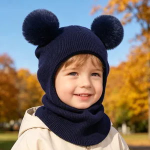 Close-up of kids' navy knit balaclava featuring fluffy double pom-poms and ear protection