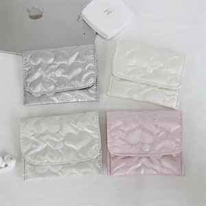 Set of four heart-patterned quilted small pouches in silver, cream, and pink colors