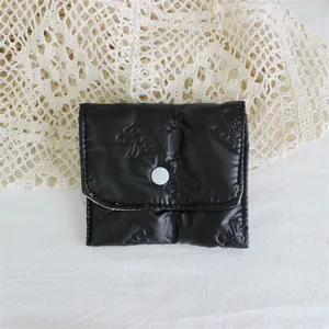 Close-up of black quilted PU leather pouch with cute bow embossing and snap button