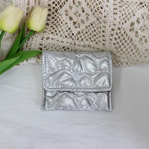 Macro view of silver heart-quilted PU leather pouch showing the button closure.
