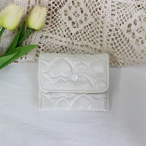 Close-up of white quilted PU heart-patterned small storage pouch with snap button