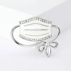 Creative silver-toned medical mask brooch with sparkling rhinestones and a bow accent.