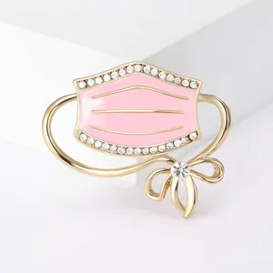 Elegant pink medical mask shaped brooch with sparkling crystals and a golden bow