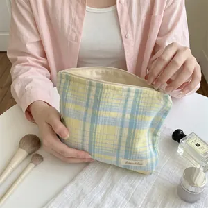 Detailed close-up showing a hand opening a colorful plaid cotton cosmetic storage bag