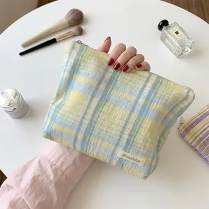 Detail of a large capacity plaid cosmetic bag with soft yellow and blue checkered pattern.