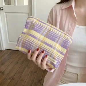 Detail of the purple and yellow plaid cosmetic bag held in hand for scale and style.
