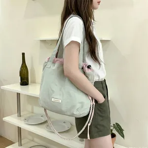 Side view of a woman carrying a large sage green and pink canvas tote bag in a room