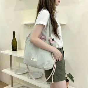Model carrying a light green large capacity canvas tote bag with pink drawstring detail