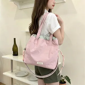 Detailed view of pink canvas tote bag with drawstring closure and woven shoulder strap