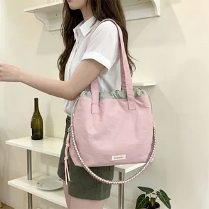 Asian woman carrying a large pink and grey canvas tote bag in a minimalist room