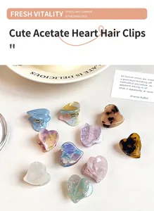 Variety of colorful acetate heart-shaped small hair claw clips on a white surface.