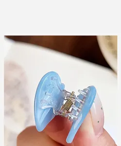 Close-up detail of a blue acetate heart-shaped hair claw clip with golden spring