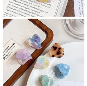 Close-up of small acetate heart-shaped hair claw clips in various marble patterns.