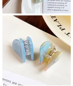 Close-up of small heart-shaped acetate hair claw clips in blue and marbled colors