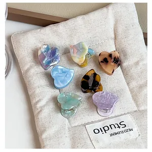 Macro view of various colorful acetate heart-shaped small hair claw clips on a pouch.