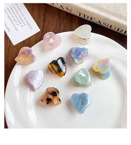 Detail view of colorful heart-shaped acetate mini hair claw clips in various colors
