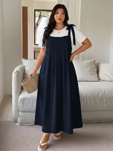 Full-body view of a plus size navy blue overall dress layered over a white t-shirt
