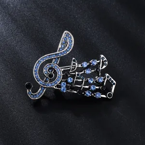 Detailed macro view of a vintage musical note brooch with blue and black rhinestones.