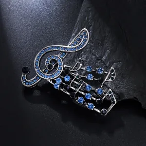 Detailed view of music note brooch with shimmering blue rhinestones on black rock