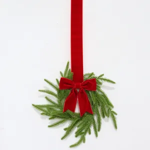 Detail of Norfolk pine Christmas wreath with elegant red velvet ribbon and bow.