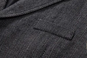 Detailed macro shot of vintage grey herringbone wool fabric on a men's casual suit vest
