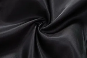 Macro detail of smooth black suit vest fabric showing fine texture and sheen.