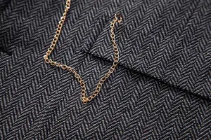 Close-up detail of the gold decorative chain on a vintage grey herringbone vest fabric