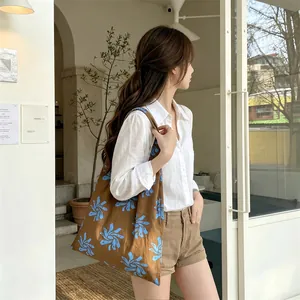 Floral canvas tote bag carried over the shoulder by a model in a casual cafe setting