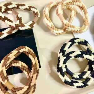 Macro detail of coffee-toned braided twist hair ties showing elastic rope texture.
