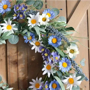 Dettaglio di una ghirlanda primaverile con margherite artificiali blu e bianche