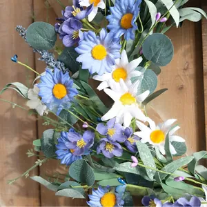 Dettaglio ravvicinato di margherite artificiali blu e bianche su una ghirlanda di fiori