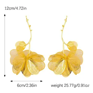 Detailed view of oversized golden hollow-out flower earrings with branch hook