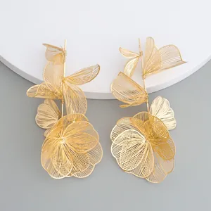 Detailed macro view of golden hollowed flower earrings featuring intricate metal petals