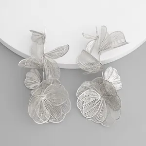 Close-up macro of silver-tone hollowed-out stereo flower drop earrings for women