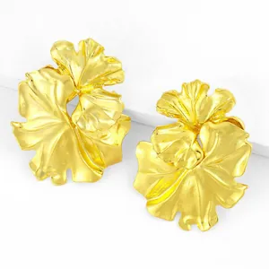 Detailed view of oversized 3D golden flower statement earrings with textured petals