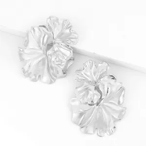 Detailed close-up of large silver metallic 3D ruffled flower petal fashion earrings