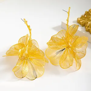 Detail shot of oversized gold hollow-out floral drop earrings with branch stems.
