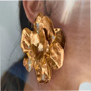Detailed macro view of an oversized hammered gold metallic flower statement earring
