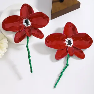 Detailed close-up of vibrant red enamel orchid flower drop earrings with green stems