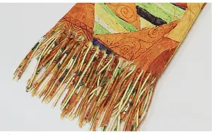Close-up detail of colorful tassels and artistic oil painting pattern on warm shawl
