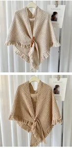 Detail view of knitted triangle shawl with fringes and brown leather buckle