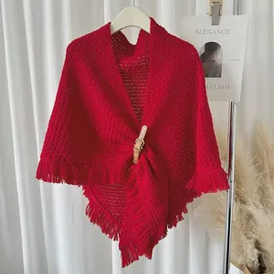 Close-up of elegant red knitted triangular shawl with tassel and leather buckle detail.