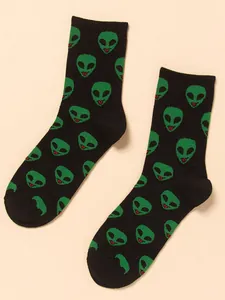 Close-up of trendy black mid-calf socks featuring a vibrant green alien head pattern