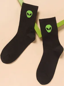 Close-up of black mid-calf socks featuring a vibrant green alien head embroidery
