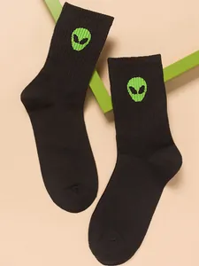 Detail shot of black crew socks featuring a vibrant green embroidered alien head motif.